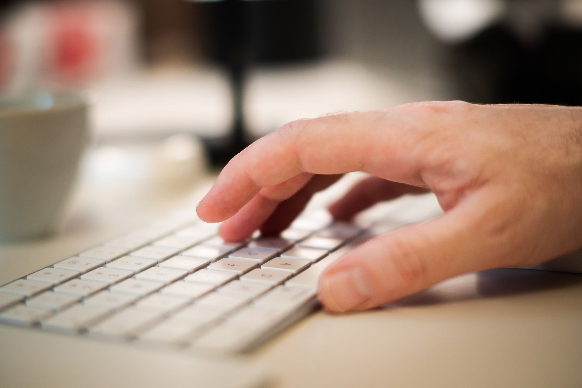 Nærbilde av en mann som skriver på et tastatur, i et arbeidsmiljø