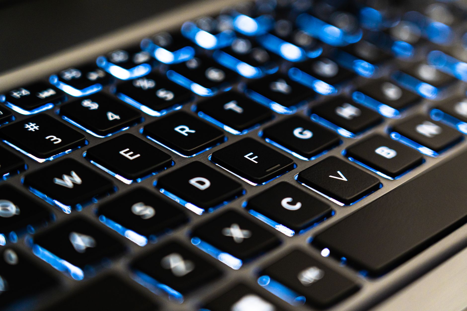 Detaljert nærbilde av et bakbelyst tastatur med blått lys, for teknologifølelse